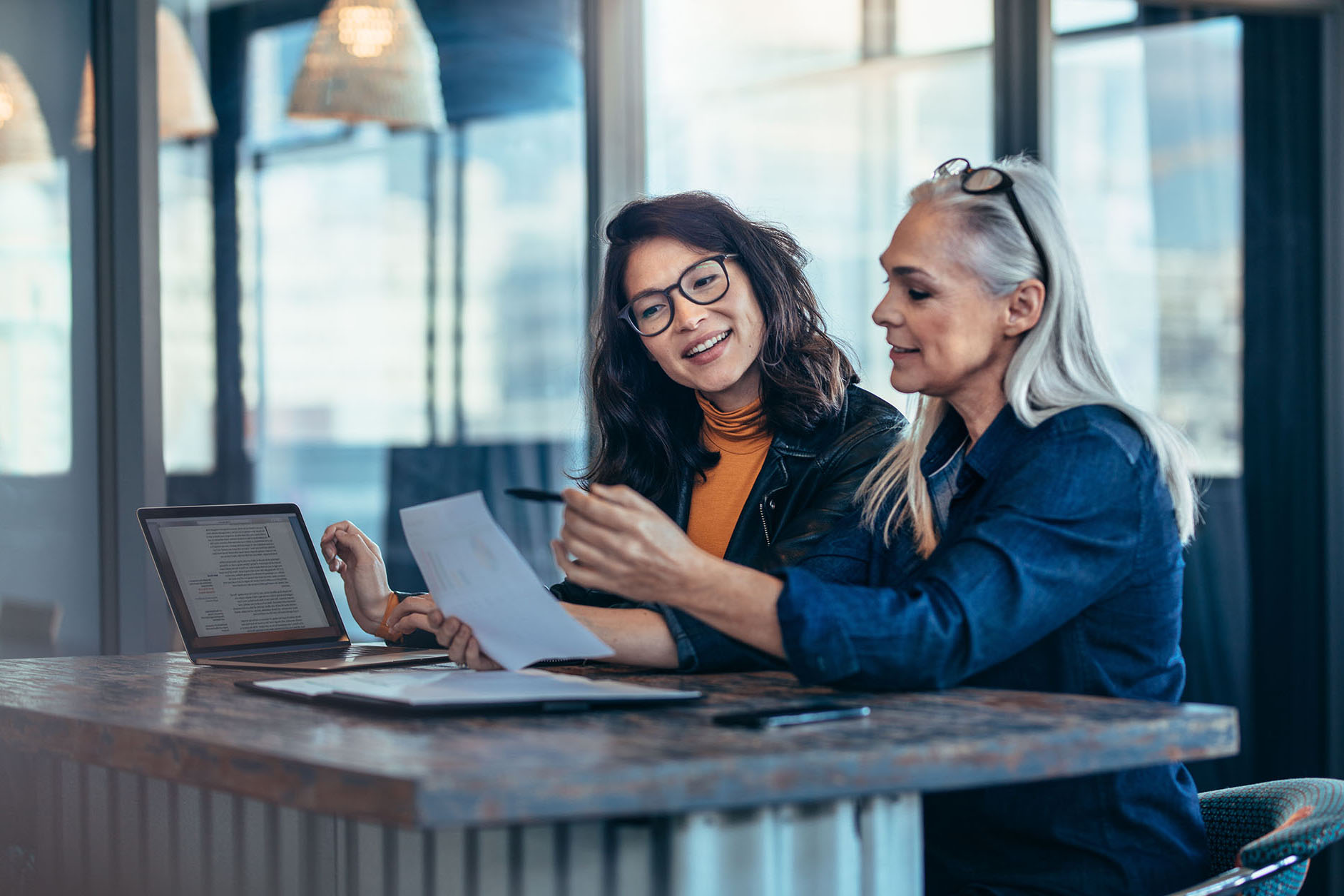 Two women analyzing documents at office